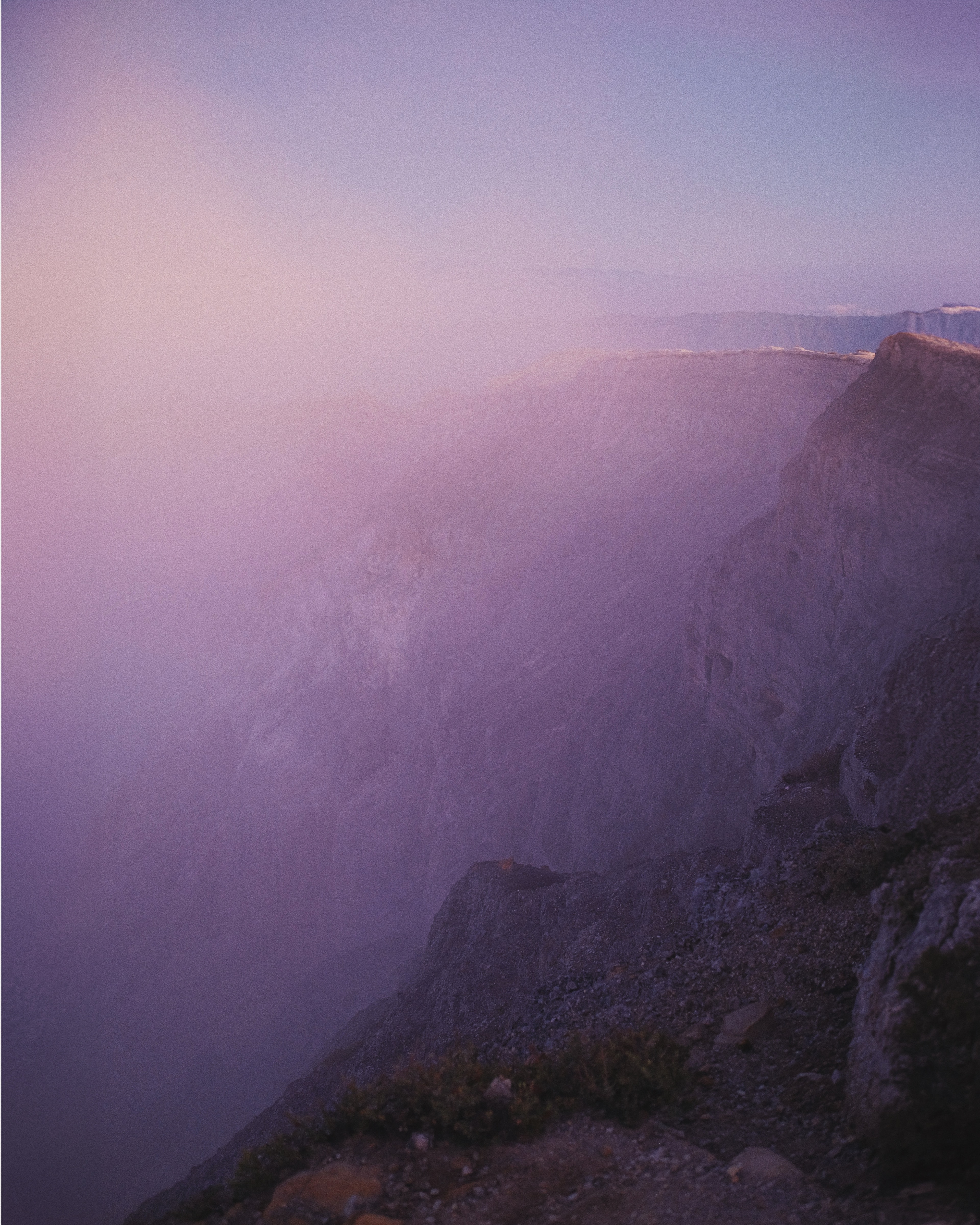 Rocky ridges fading into pink and purple mist.